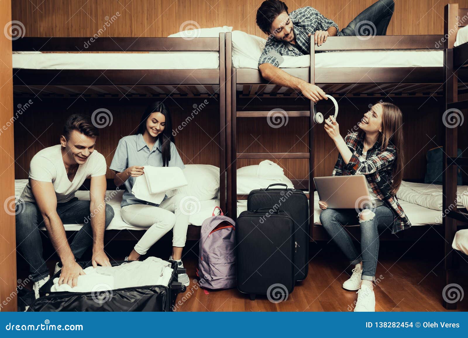 Friends unpack luggage and listen to music. Hostel for Young People. Best Friends Traveling. Small Room in Hostel. spend time Together. bunk beds in room. smiling People. Communicate. occupy seats. sit and lie on bed. unpack luggage