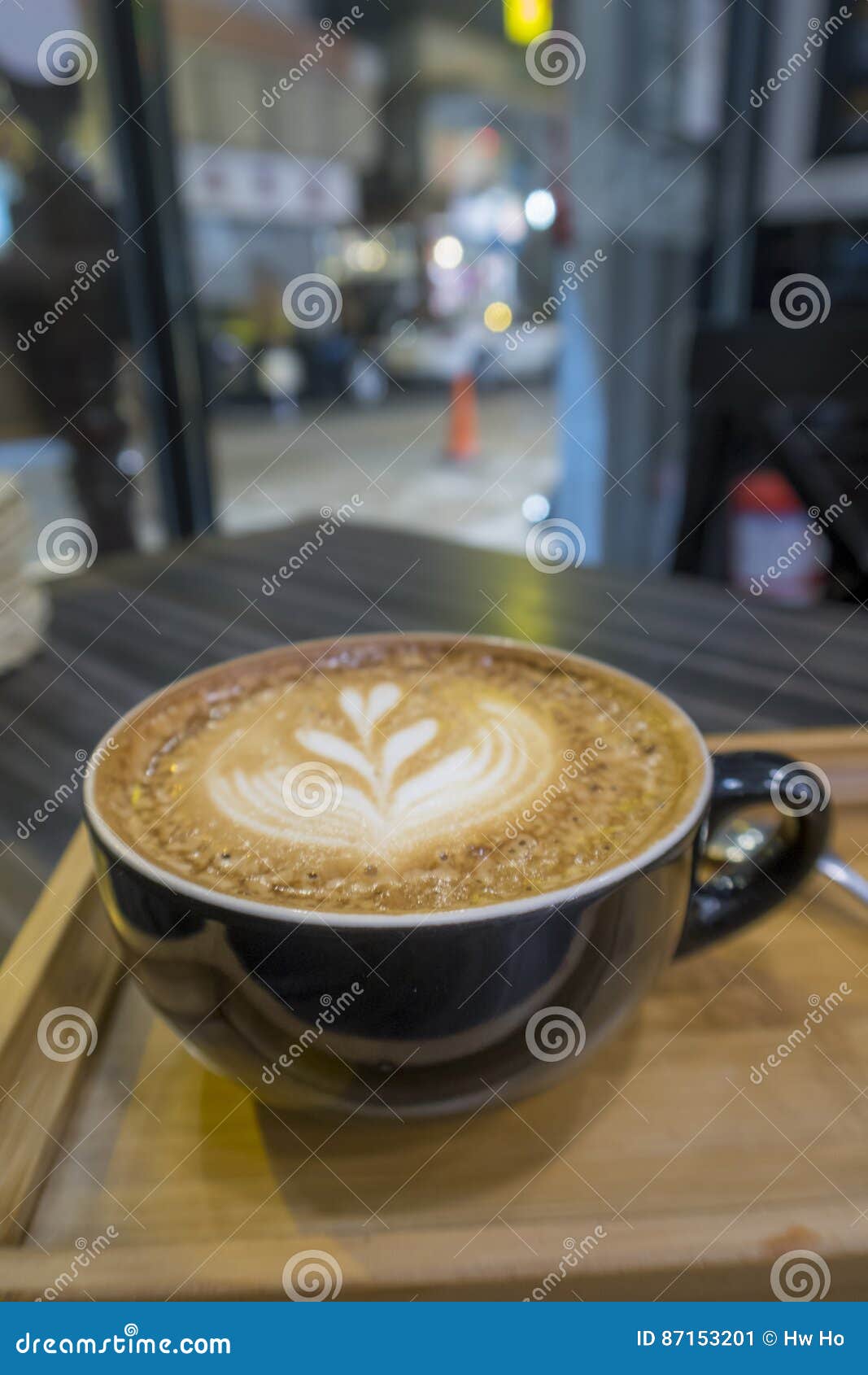 Hot Art Latte Coffee in a Cup on Wooden Tray and Coffee Shop Blur