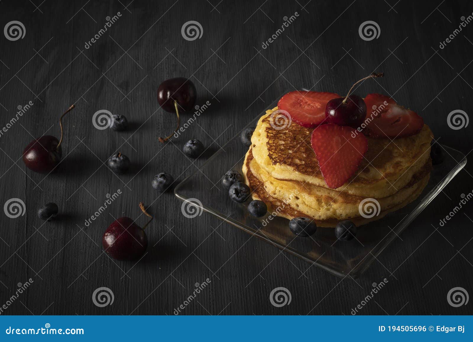 hot cakes stacked with cherries, strawberries and blueberries