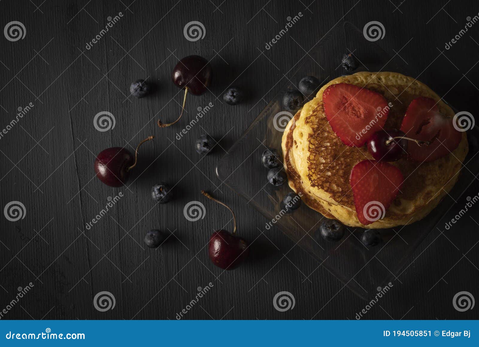 hot cakes stacked with cherries, strawberries and blueberries