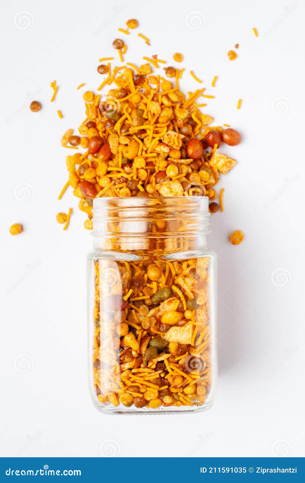 hot spicy nav ratan snacks spilled out and in a glass jar, made with red chili, peanuts, corn flakes.