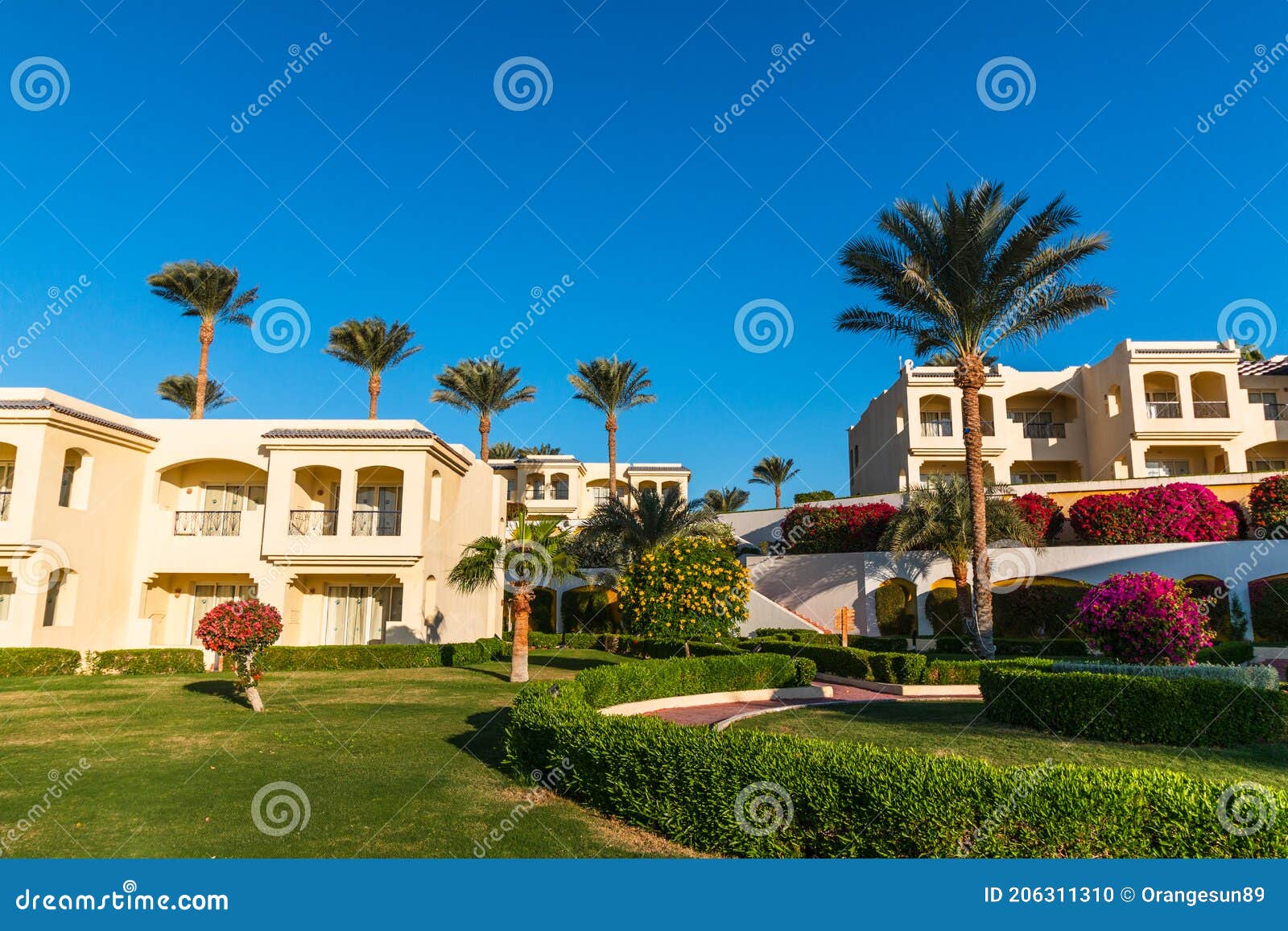 hotel suites exterior with palms, garden and blue sky