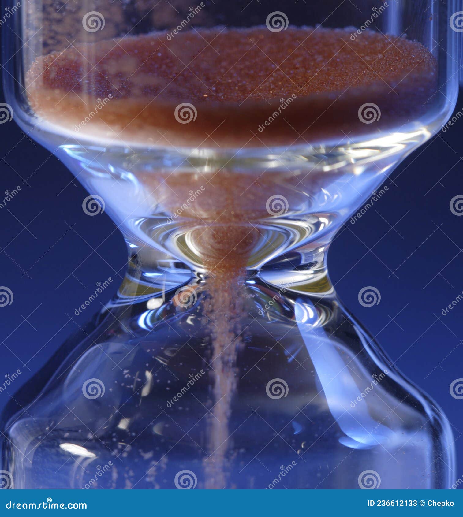 Hour Glass with Running Sand Inside, on Blue Background. Time Passing