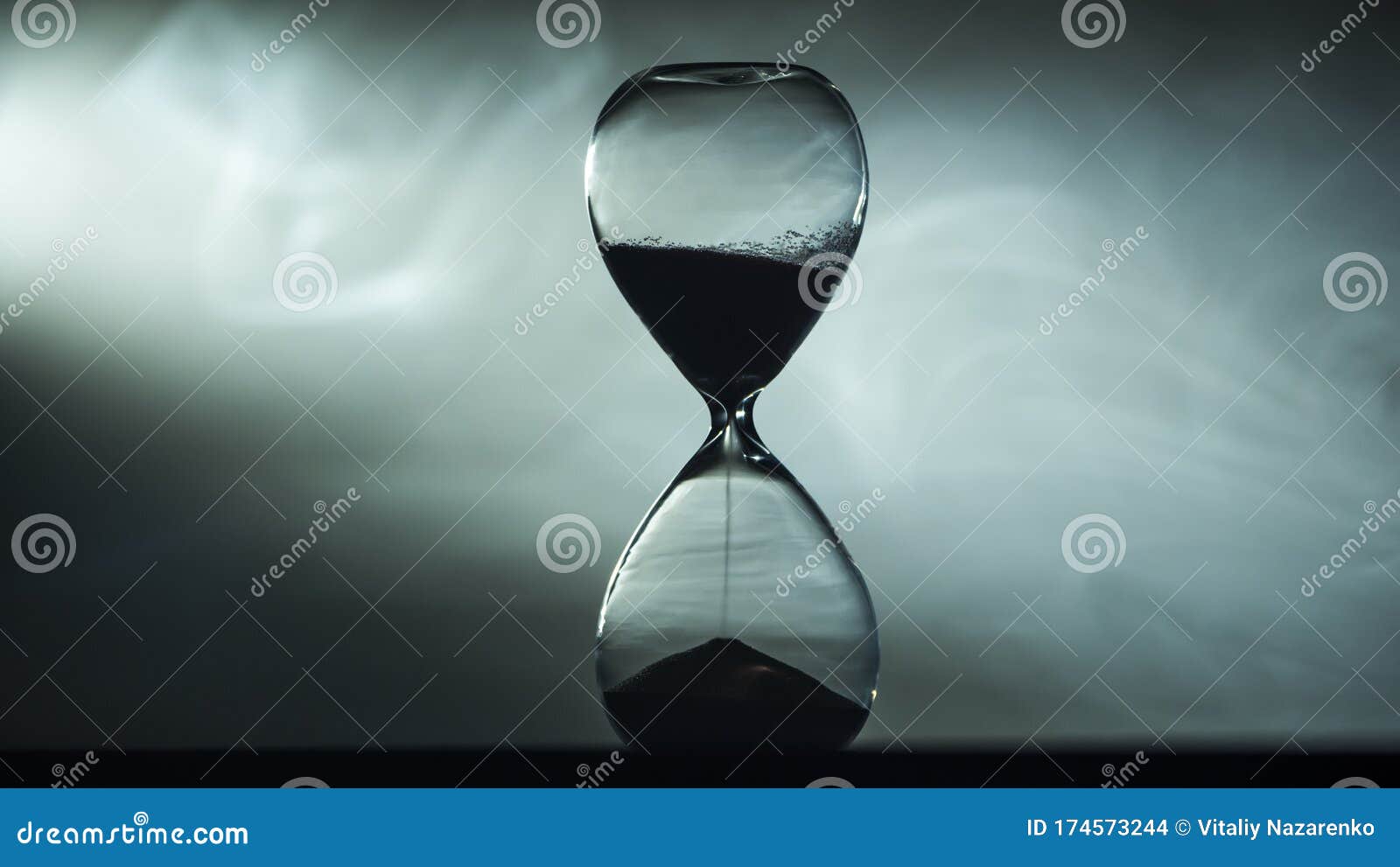 Hourglass Against the Fog Illuminated by the Spotlight Stock Photo