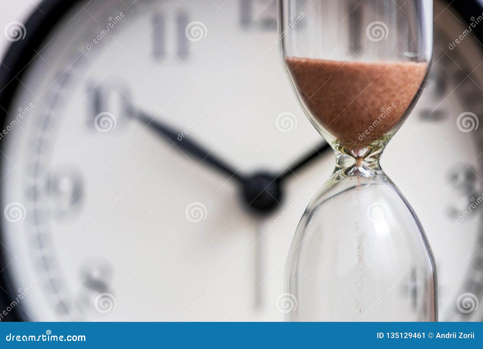 hourglass on the background of office watch as time passing concept for business deadline, urgency and running out of time. sand
