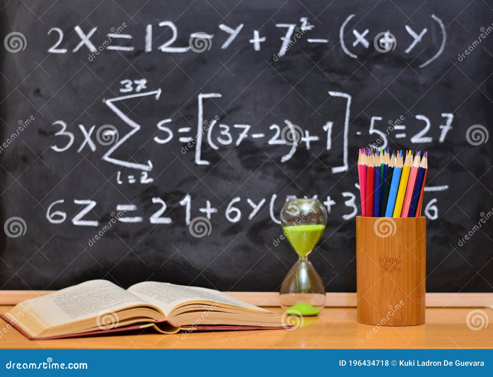 hourglass and book on a table, with a blackboard background