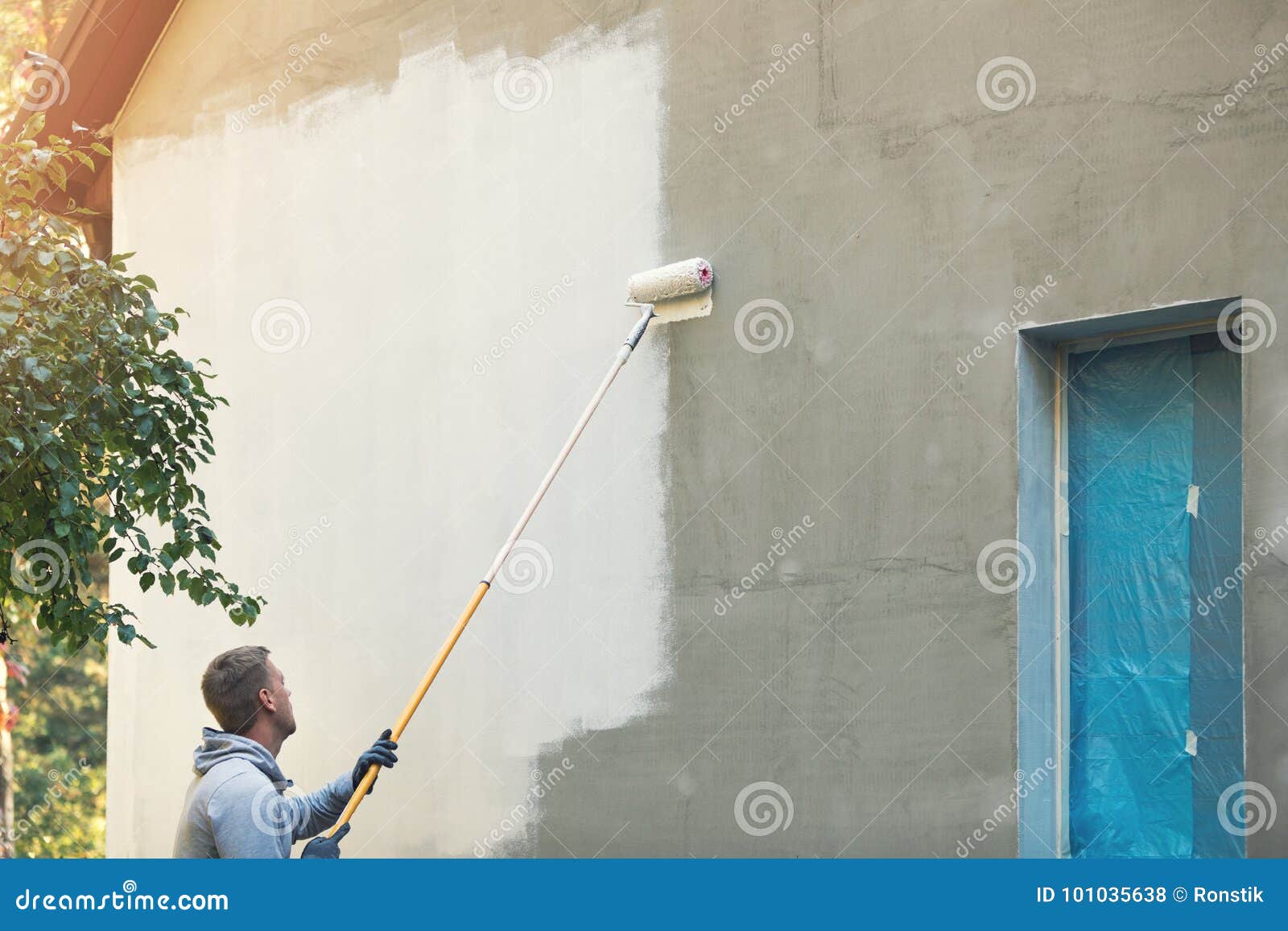 house painter painting building exterior with roller