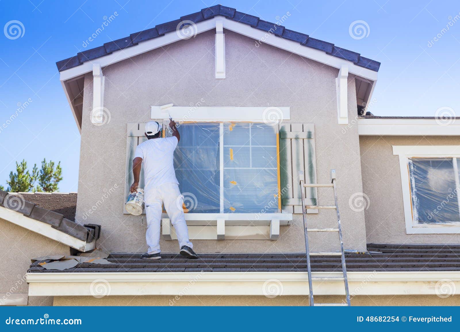 house painter painting the trim and shutters of home