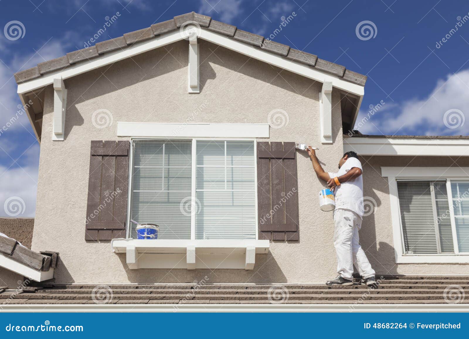 house painter painting the trim and shutters of home