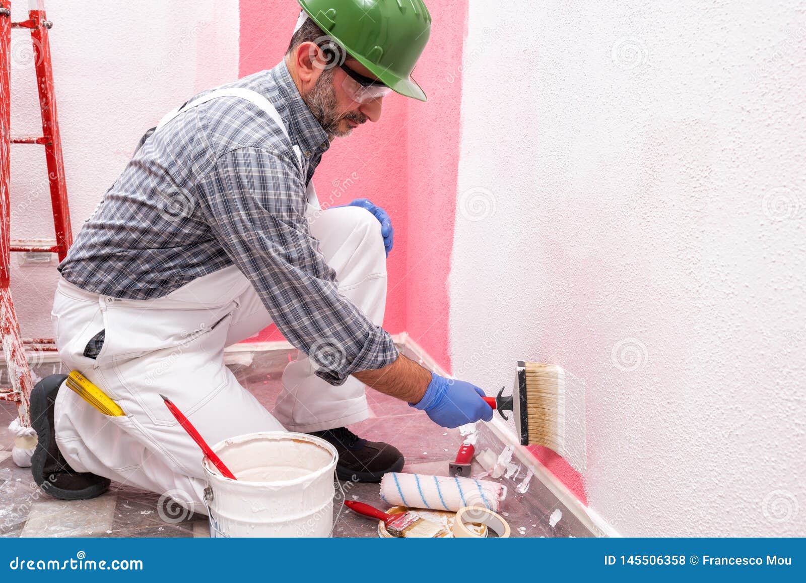 House Painter Worker at Work in the Construction Site. Building Stock