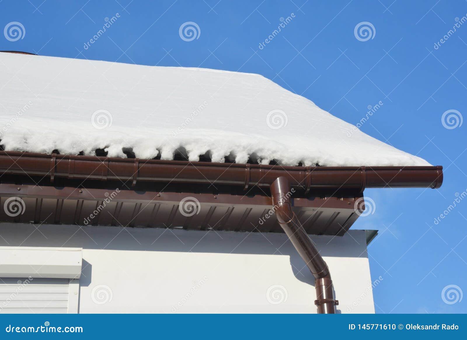 House Roof Rain Gutter in Winter, Covered Ice and Snow Stock Photo