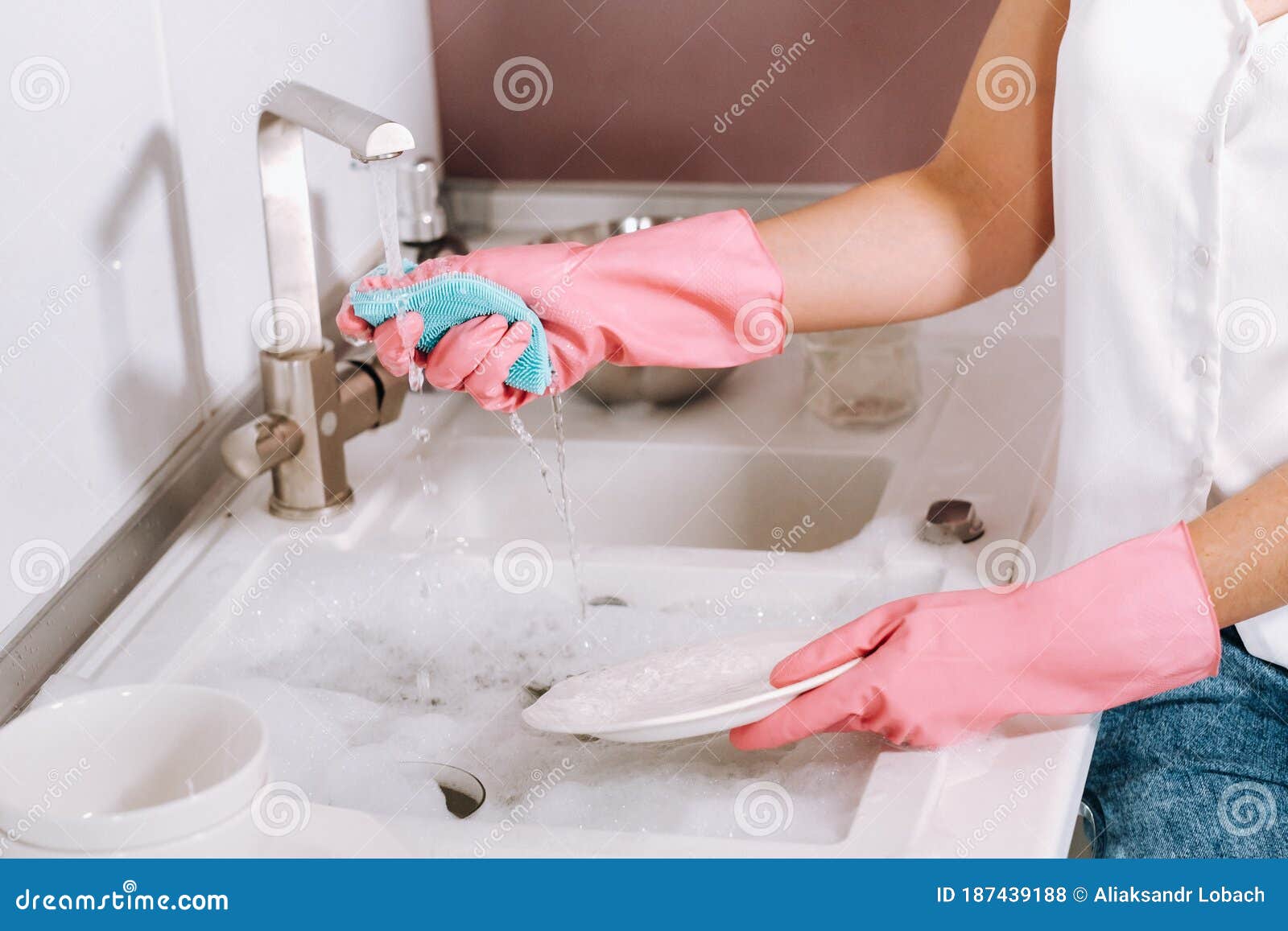 Housewife Girl in Pink Gloves Washes Dishes by Hand in the Sink w image