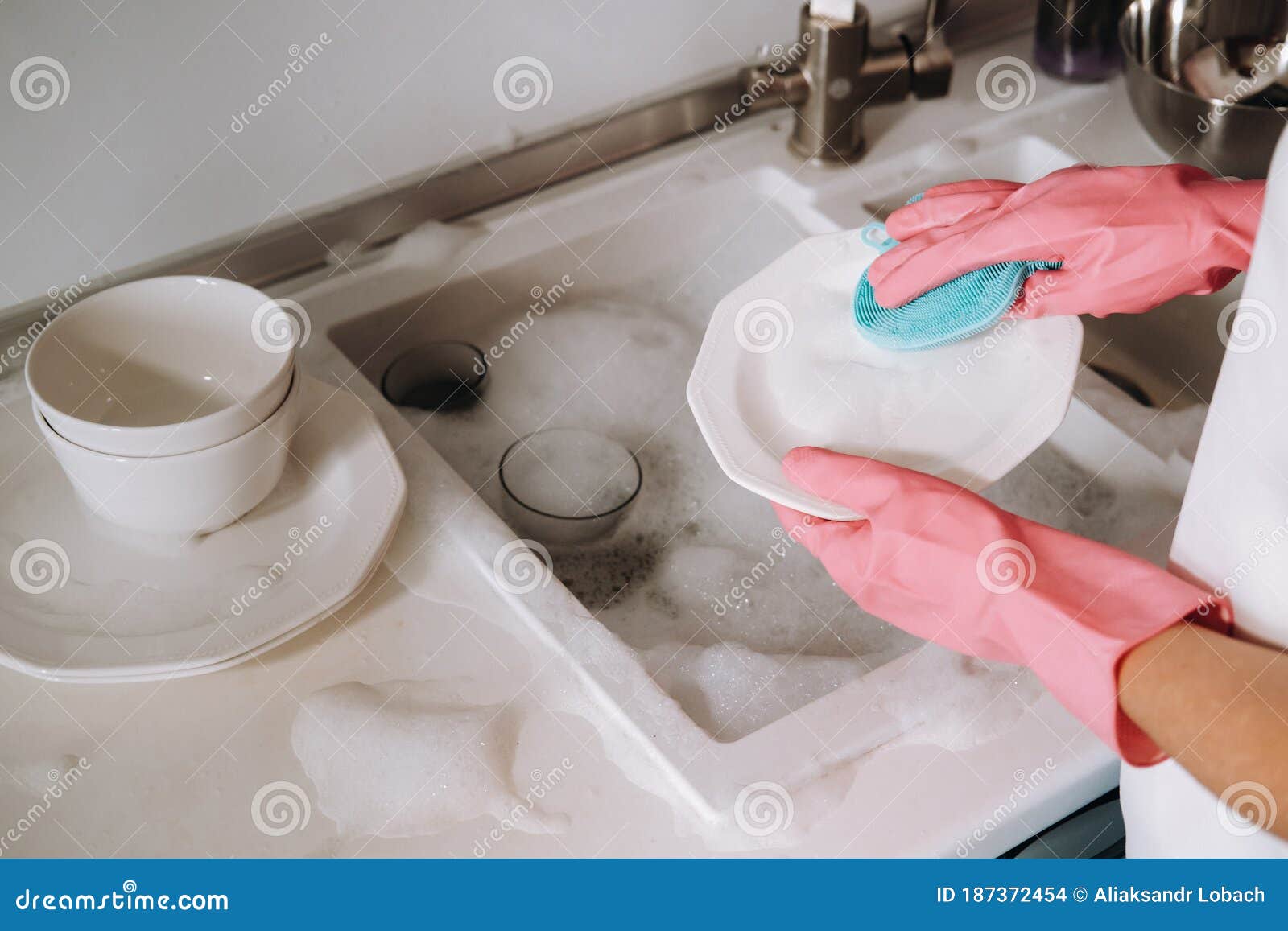 Housewife Girl in Pink Gloves Washes Dishes by Hand in the Sink w photo