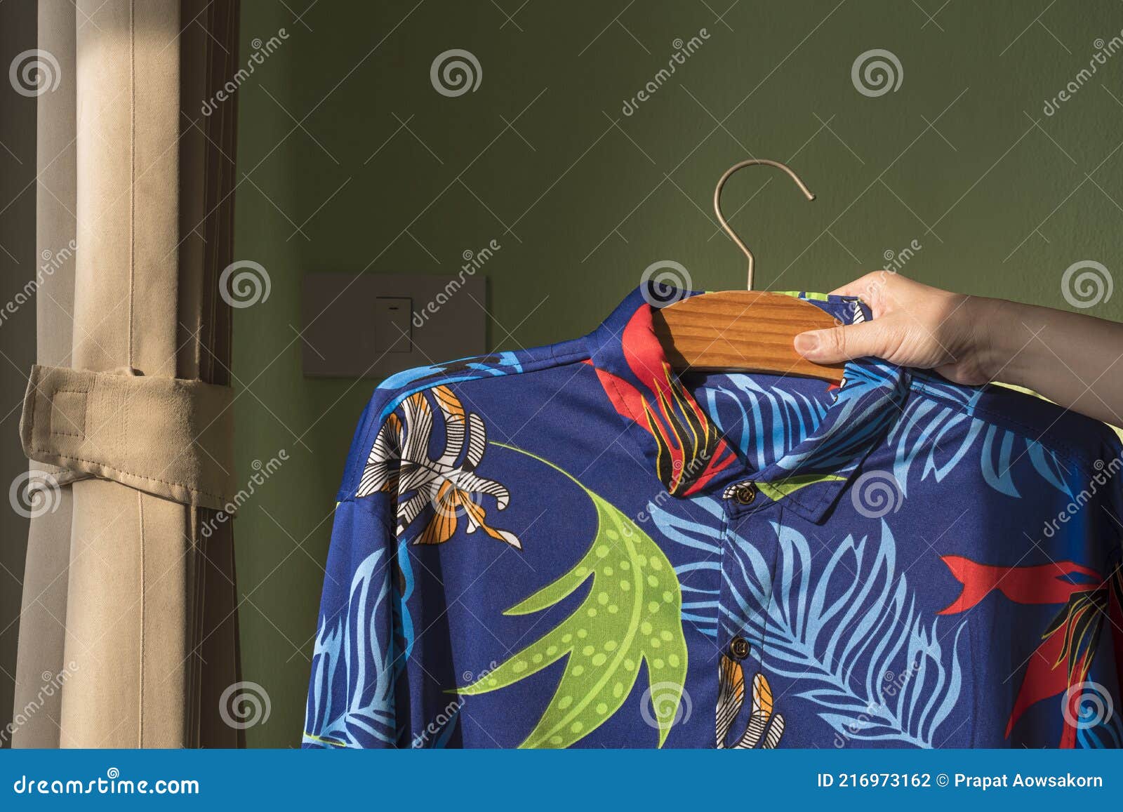Housewife`s Hand Raising Her Husband`s Hawaiian Shirt On Hanger To