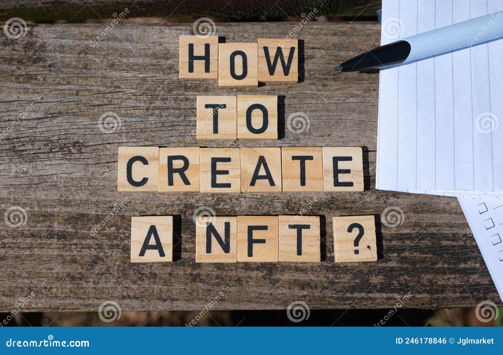 how to create a nft? black capital letter words on wooden toy blocks on a natural garden table background with paper and pencil.
