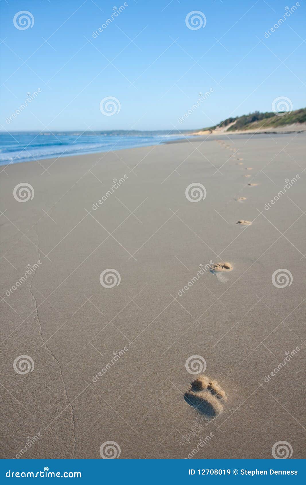 Huellas en la playa temprano por mañana en el amanecer. Sola pista de las huellas descubiertas que van a lo largo de la playa temprano por la mañana en el amanecer