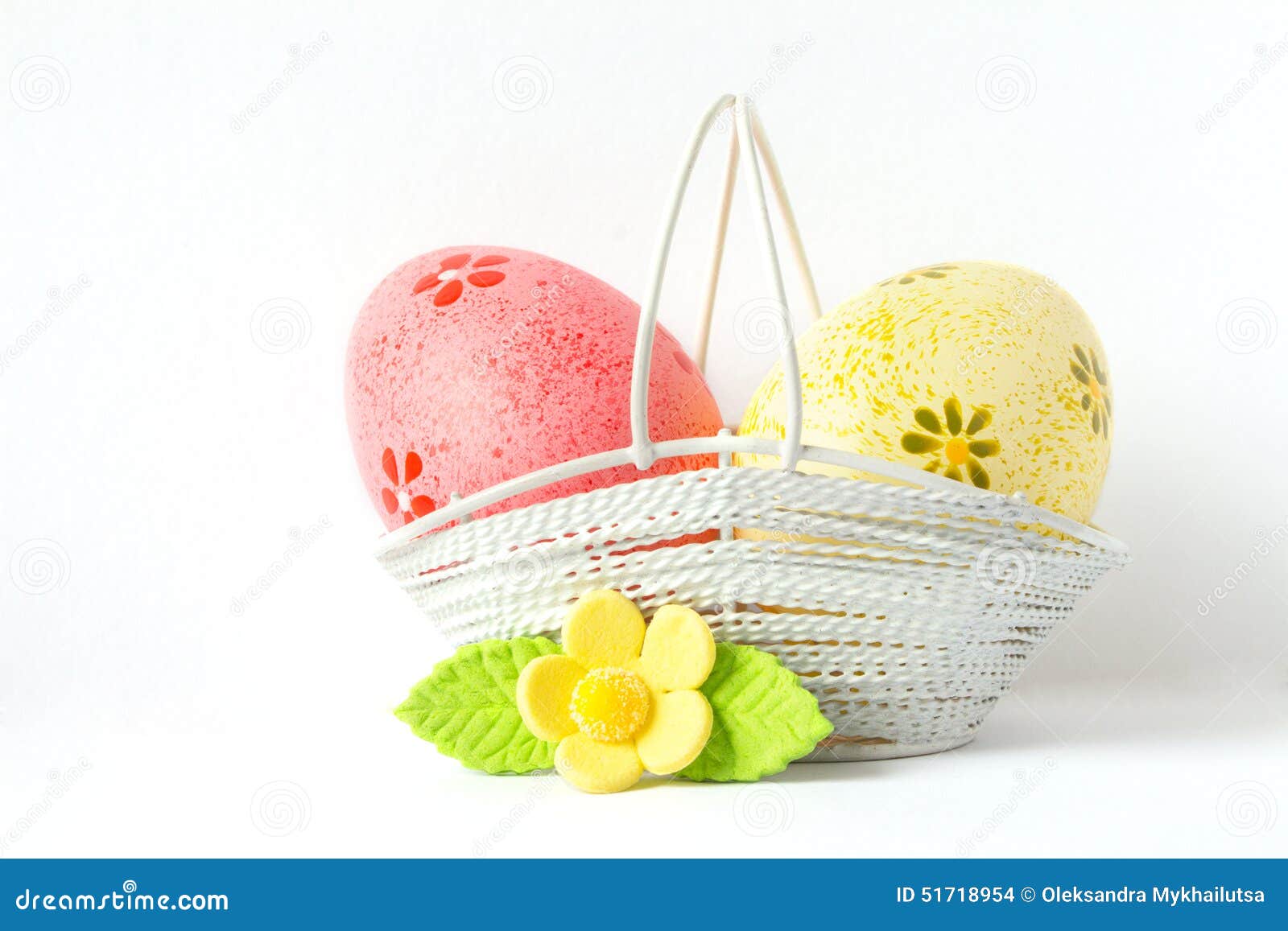 Huevos de Pascua rosados y amarillos en una cesta con la flor amarilla en el fondo blanco