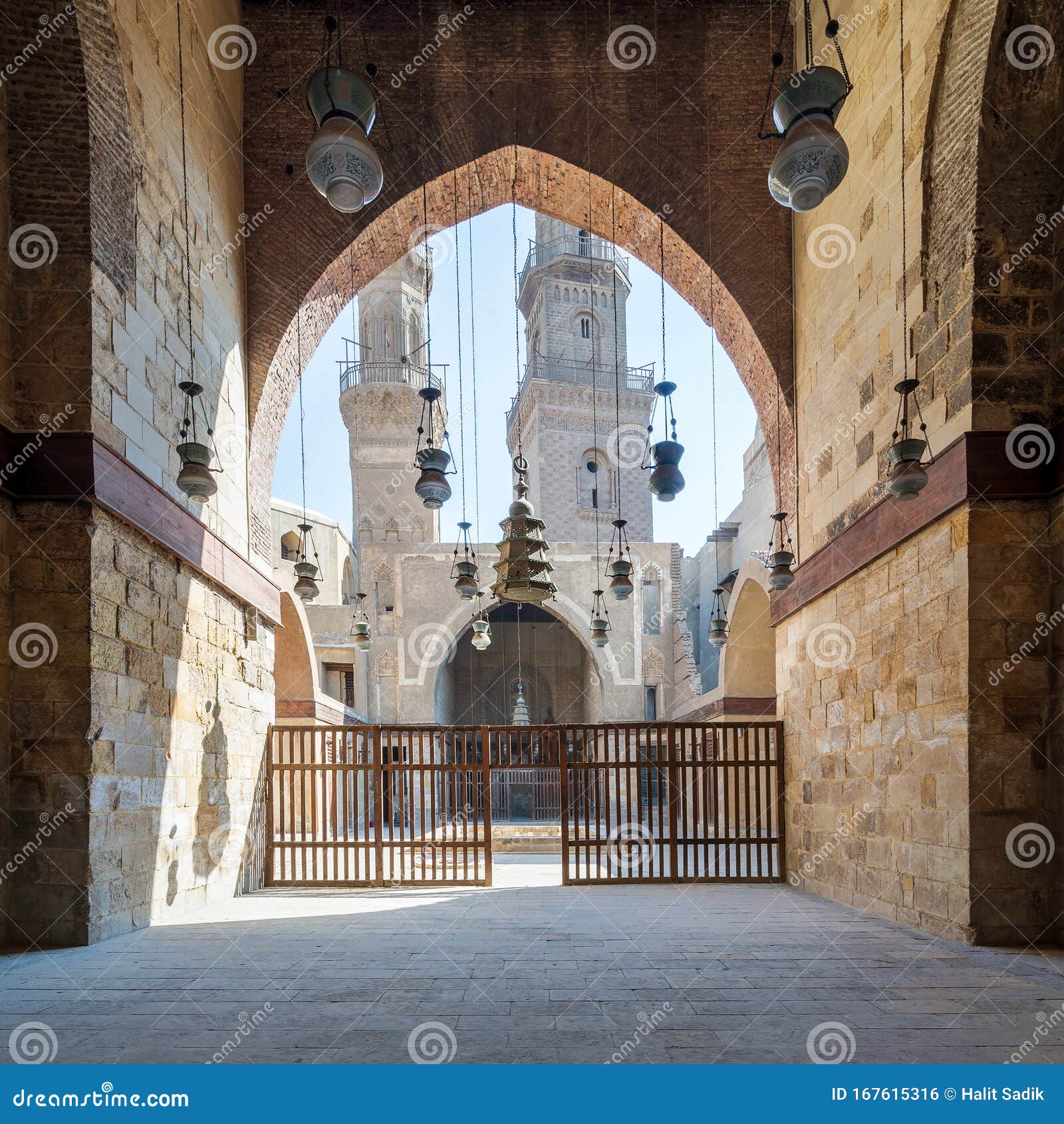 huge arch revealing patio of mamluk sultan al nassir qalawun mosque and two minarets, cairo, egypt