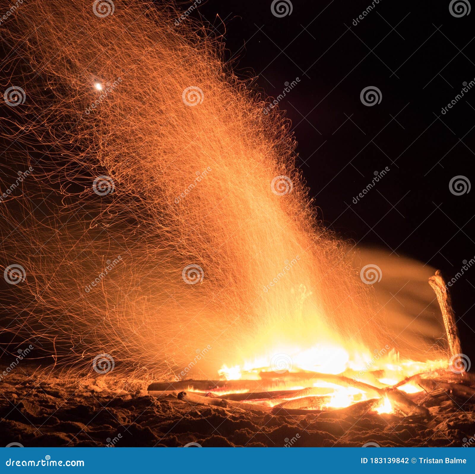 hikers crowd around a beach bonfire at the end of the heaphy trail on new zealands west coast.