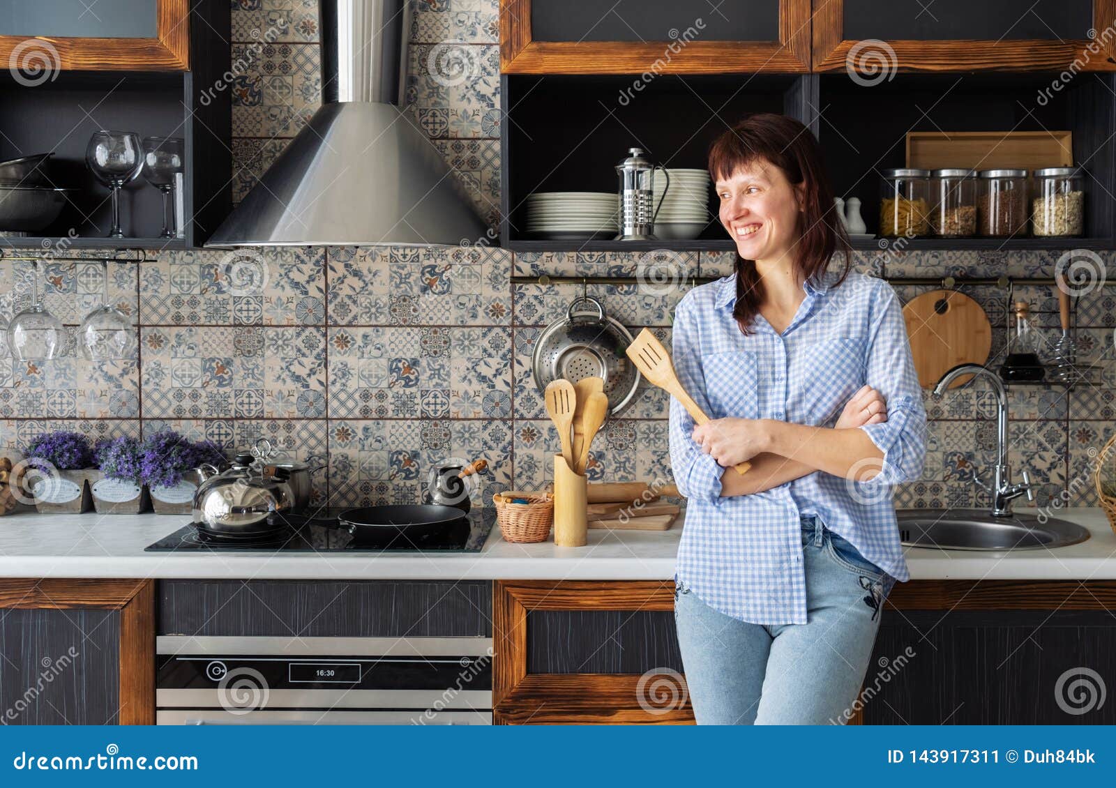 Huisvrouw: jonge vrouw met een spatel in haar handen die in de keuken glimlachen Europees stijlbinnenland Portret