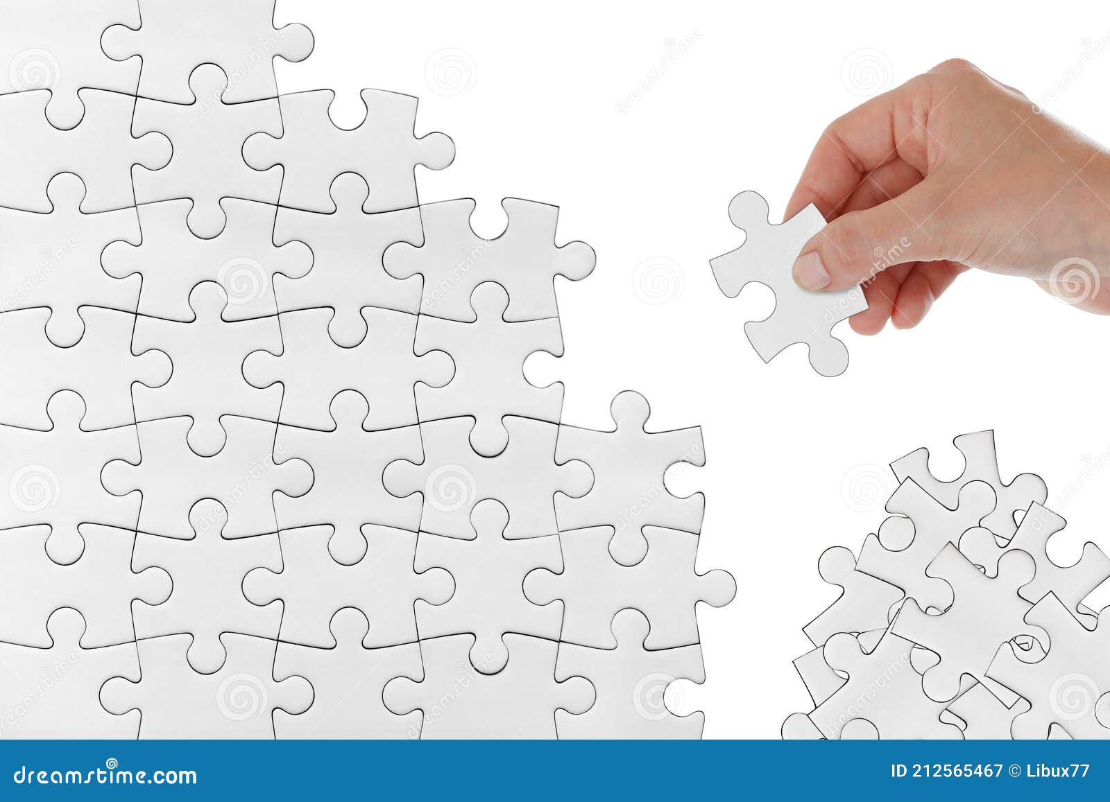 human female hand trying to connect white puzzle piece picking from heap  on white background. doing or making a jigsaw