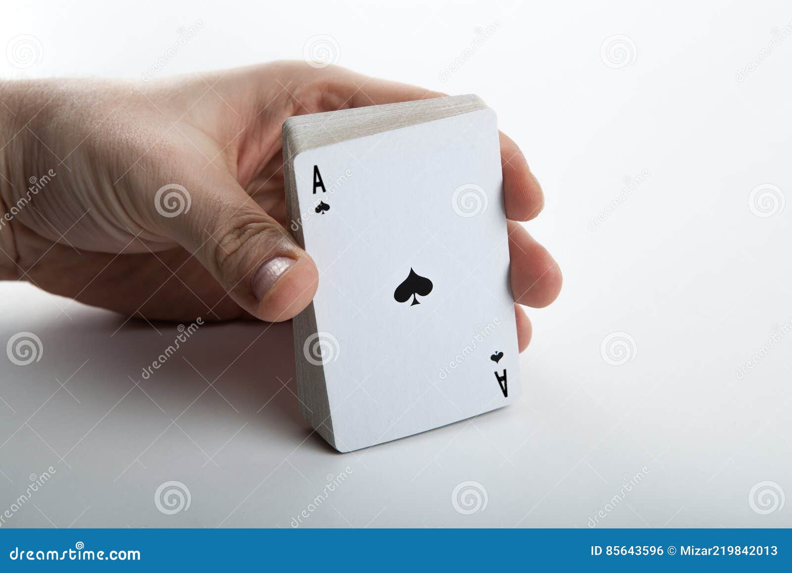 Human Hand Holding the Ace of Spades and a Deck of Cards Stock Photo