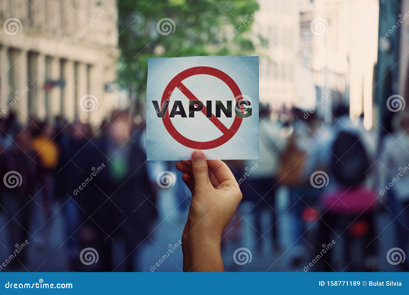human hand holding a protest banner stop vaping message over a crowded street background. banning flavored vaping products to