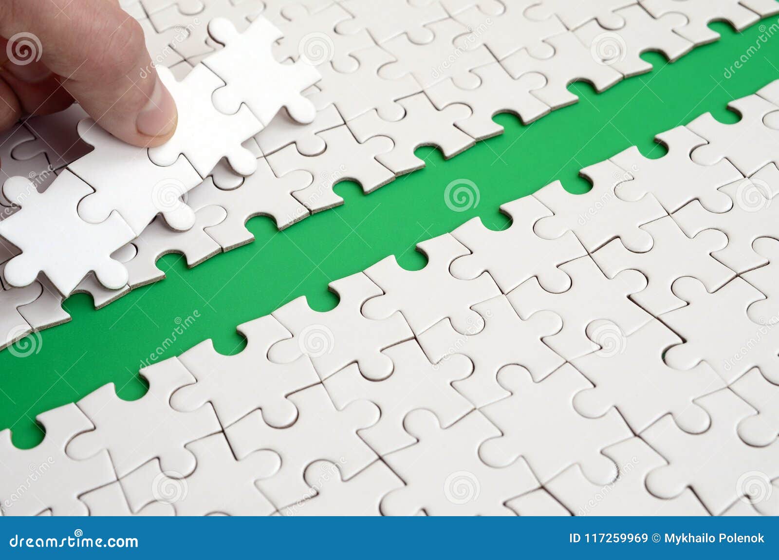 the human hand paves the way to the surface of the jigsaw puzzle, forming a green space. the concept of overcoming the difficultie