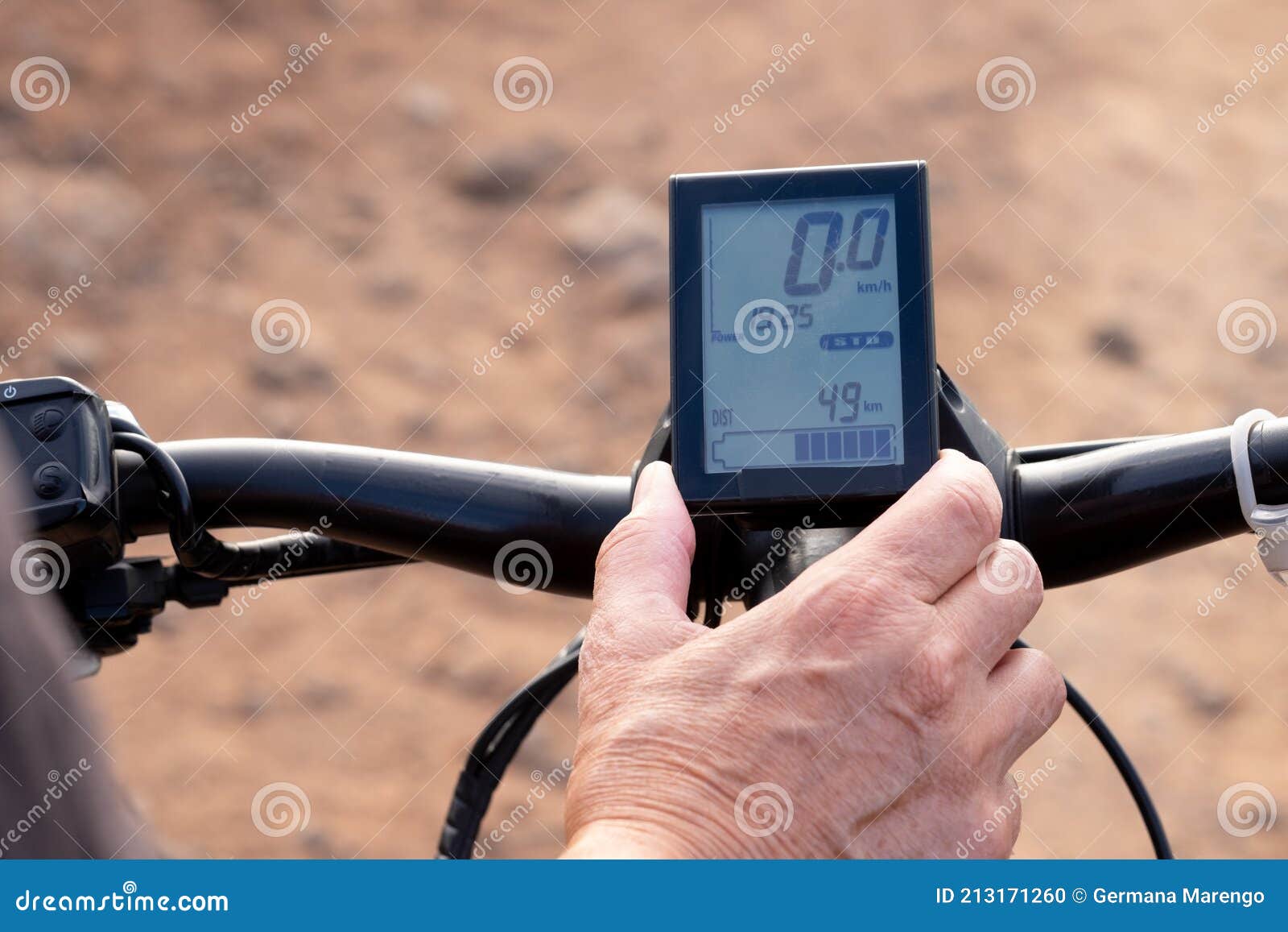Human Hand Pressing a Button on the Device of a Black Electric Bicycle