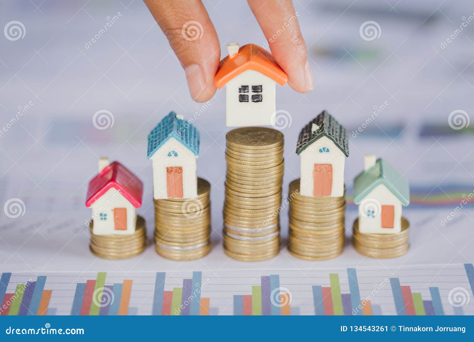 human hand putting house model on coins stack. concept for property ladder, mortgage and real estate investment