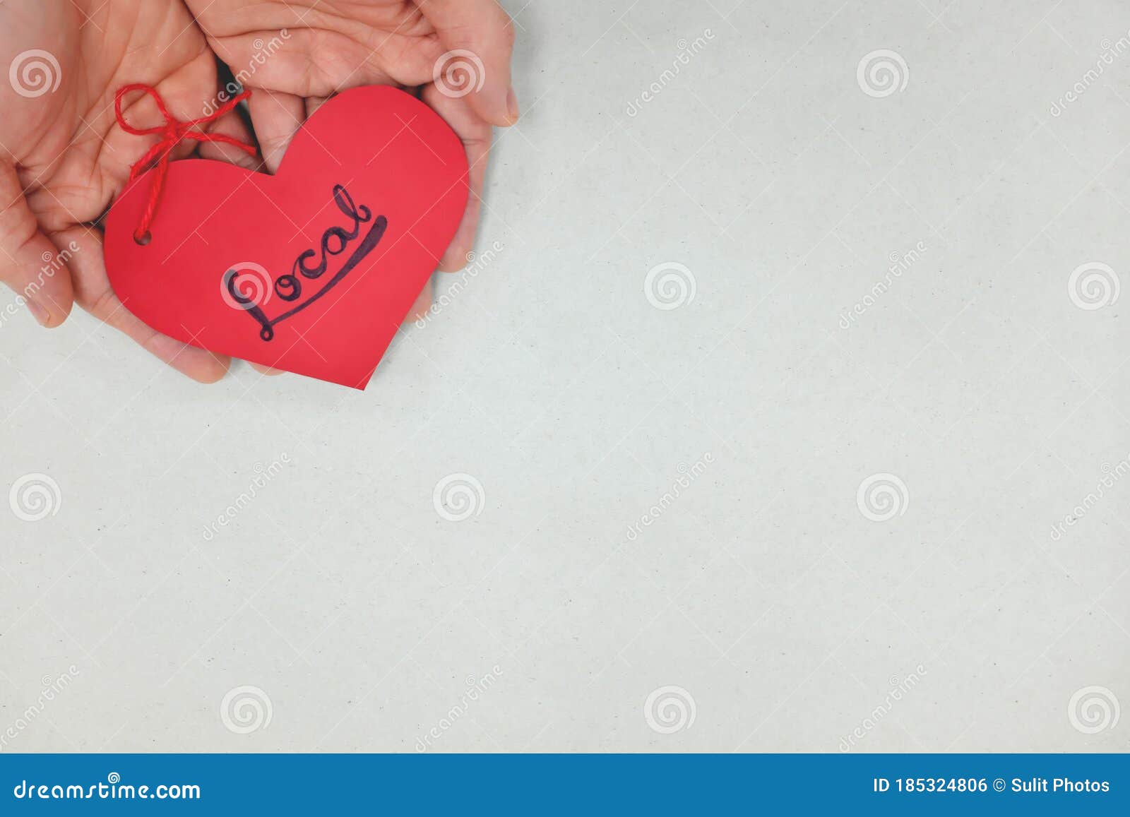 human hands holding a red heart tag with handwritten word local. support, promote, buy, shop and love local business concept.