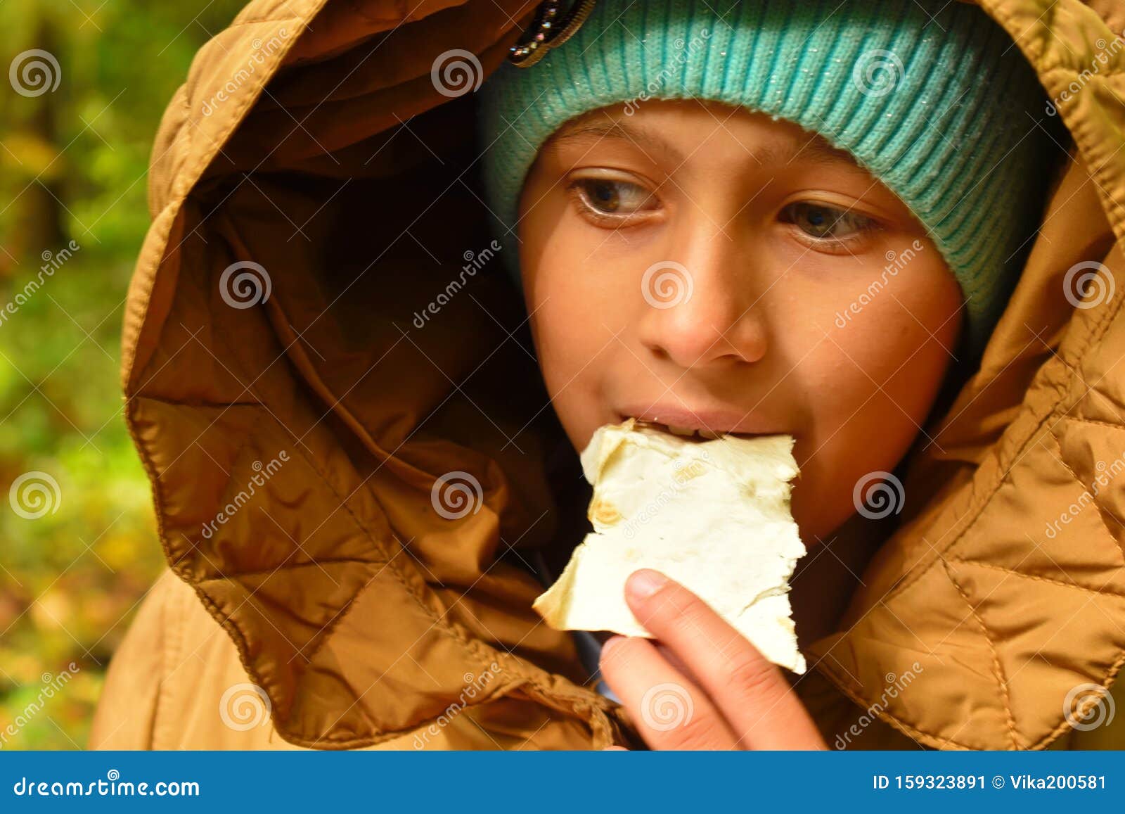 A Hungry Girl Eating Bread Outdoor. Poor Child Gnaws Cracker Stock ...