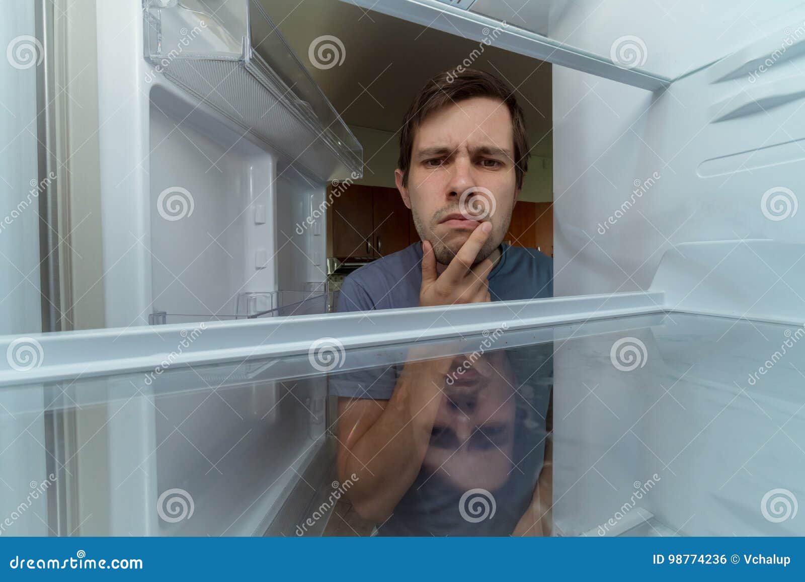hungry man is looking for food in empty fridge
