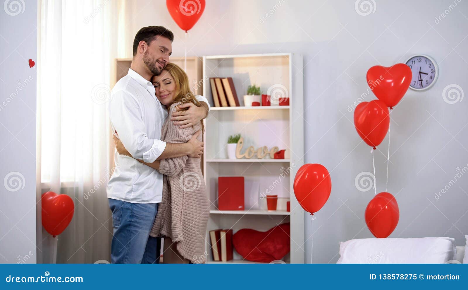 Husband Tenderly Hugging Wife in Room with Heart-shaped Balloons ... pic