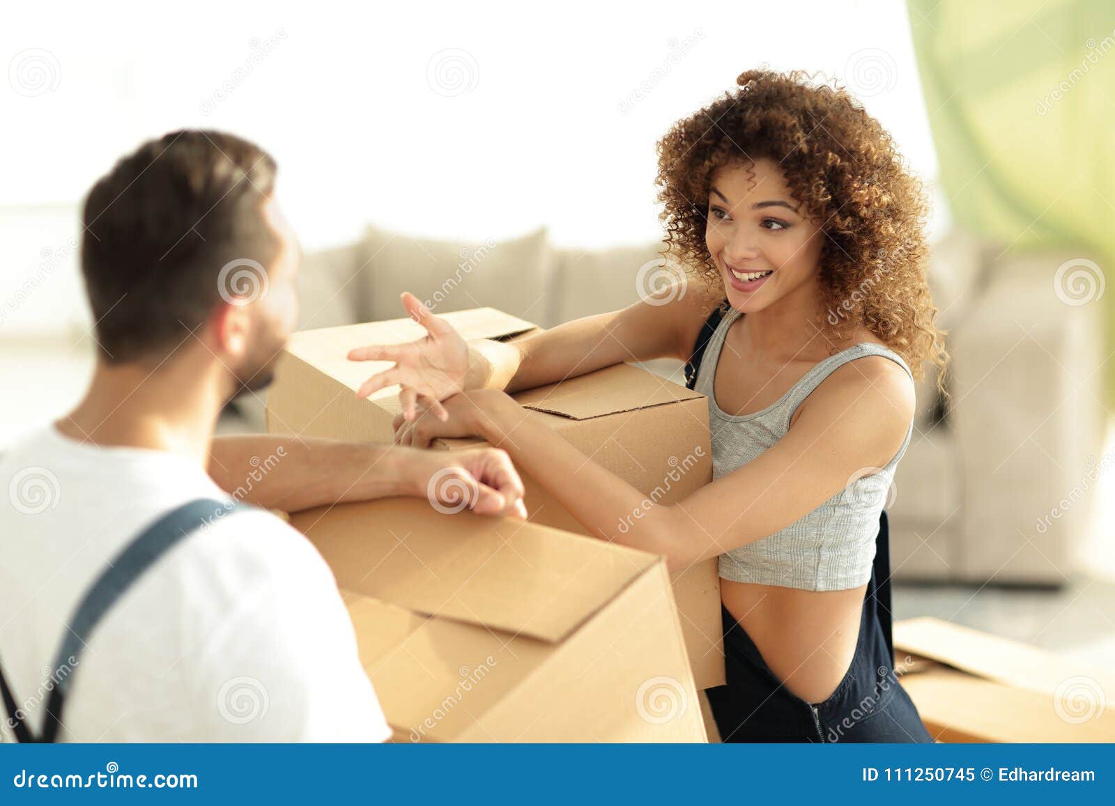  A husband and wife are discussing their finances while standing in their home, surrounded by moving boxes.