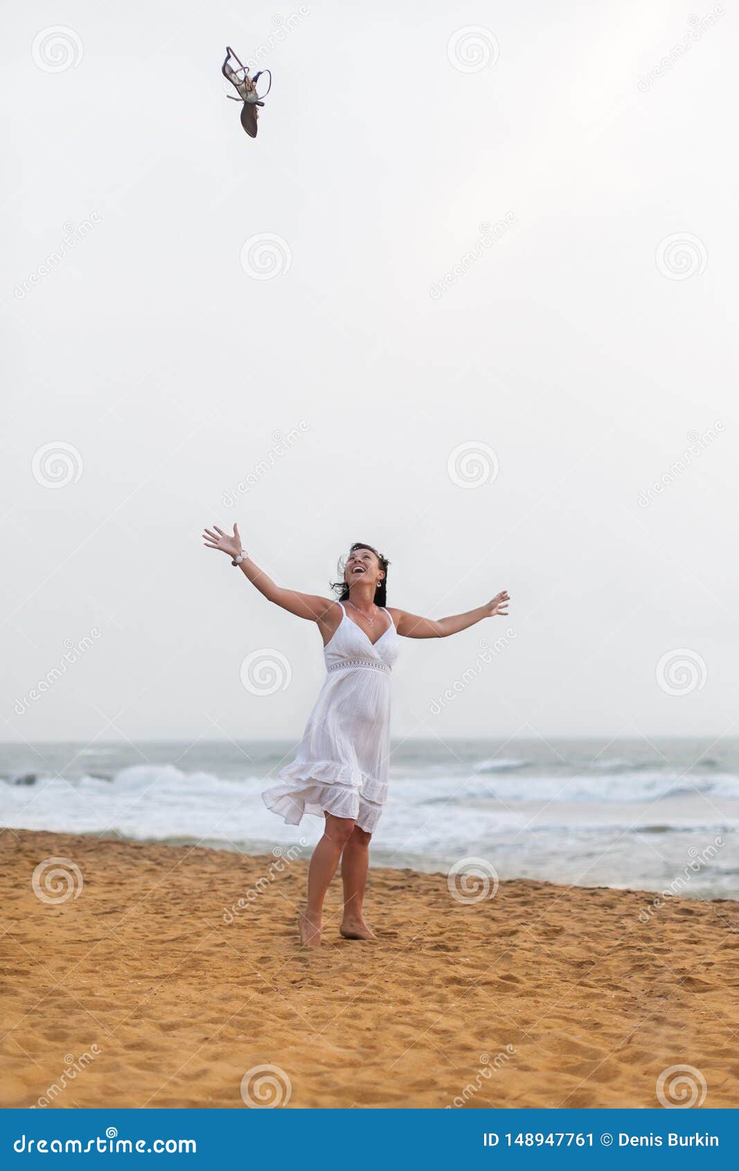 Beautiful happy woman in white dress walking on the sandy beach, throwing his sandals. travel and Summer concept.