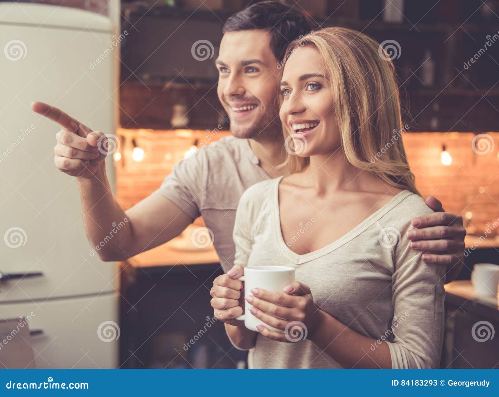 Härliga par i kök. Det härliga barnparet kramar, dricker kaffe och ler, medan stå i kök hemma