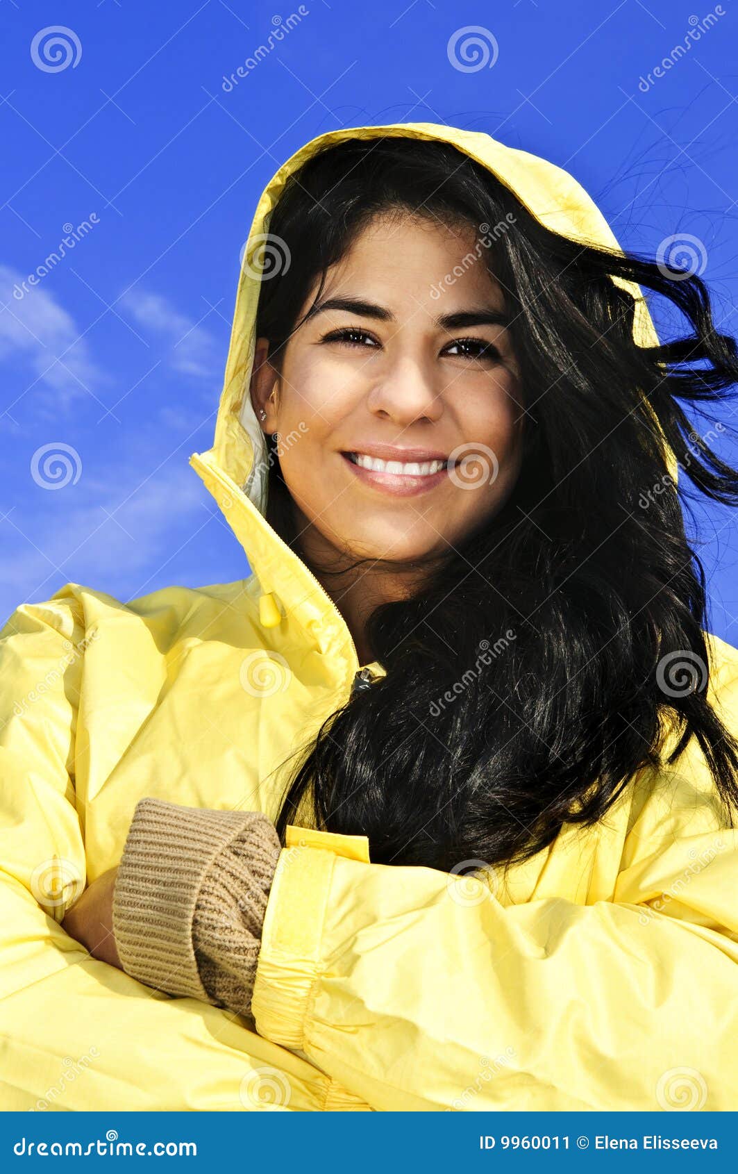 Härligt raincoatkvinnabarn. Mot le slitage yellow för härlig blå för brunettflickastående sky för raincoat