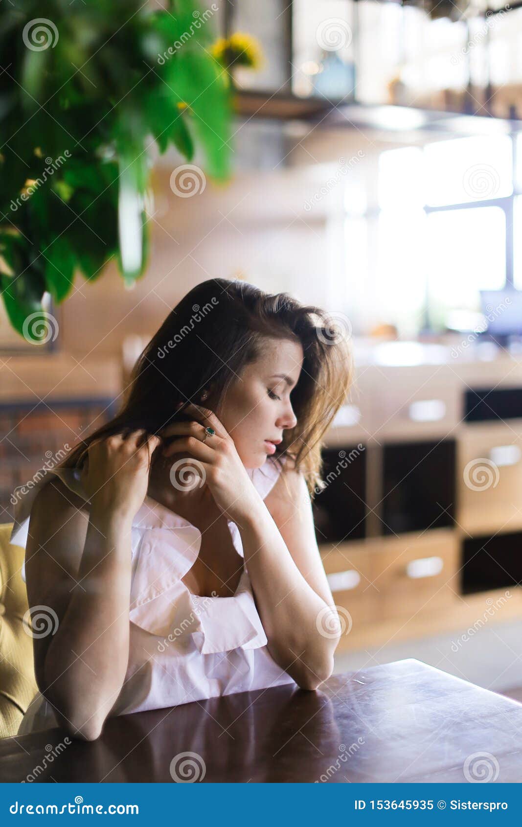Hübsche Frau, die am Café nahe grüner Raumanlage stillsteht und sitzt