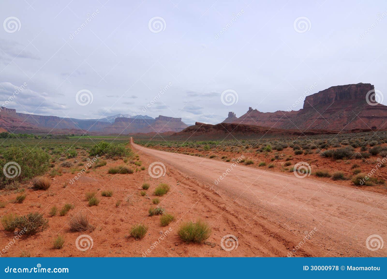 En smuts/en unpaved blytak för landsväg rakt in i öknen på långt.

Vägen är av Utah statrutt 128, nära bågar nationalpark, Moab, Utah, USA.