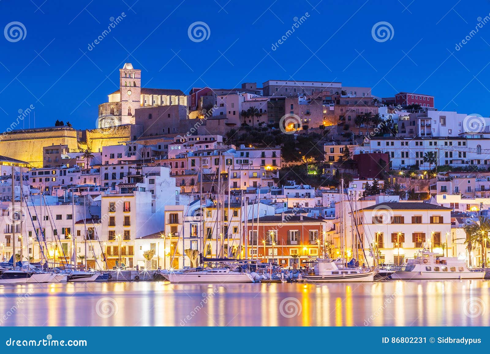 ibiza dalt vila downtown at night with light reflections in the water, ibiza, spain.