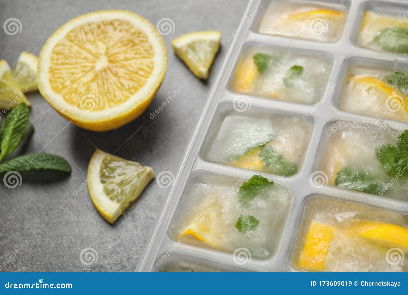 Ice Cubes with Lemon and Mint in Tray on Grey Table, Closeup Stock