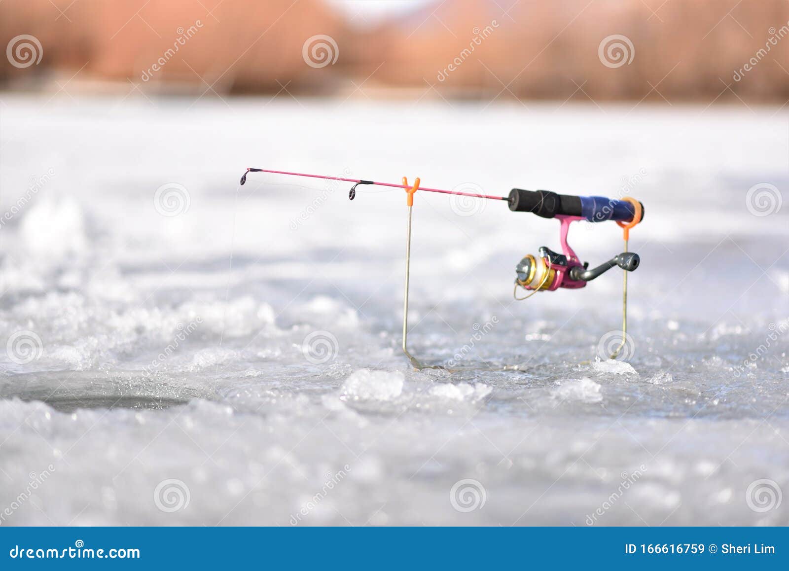 Ice Fishing Pole with Pink Real and Pole Sitting on Ice Waiting
