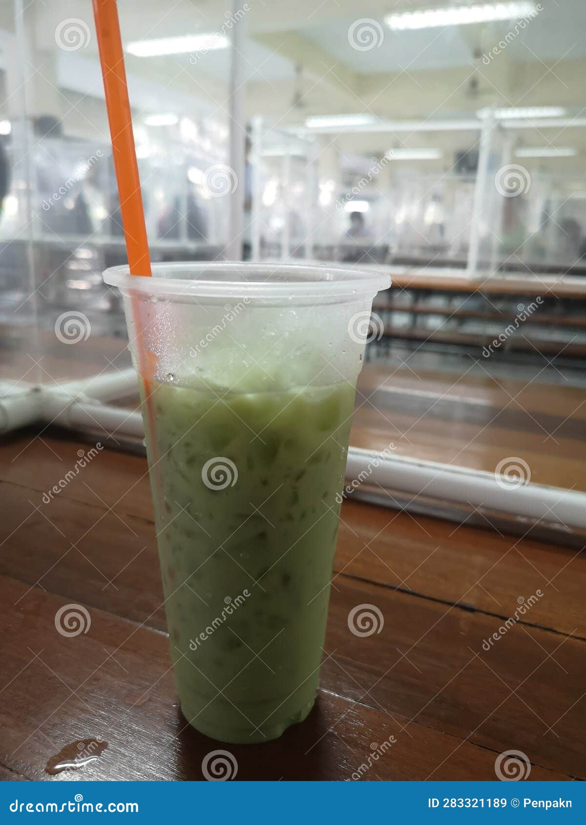 ice green tea in clear plasstic? cup on wooden table in canteen, school cafeteria