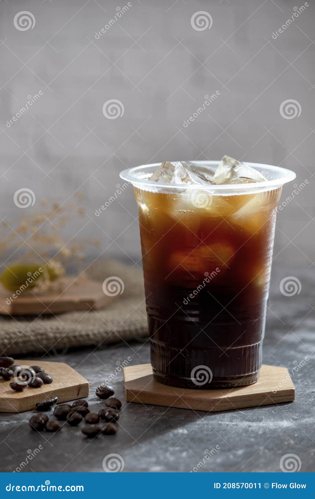 Clear Plastic Cup Half Full Of Iced Coffee With A Paper Straw Hand