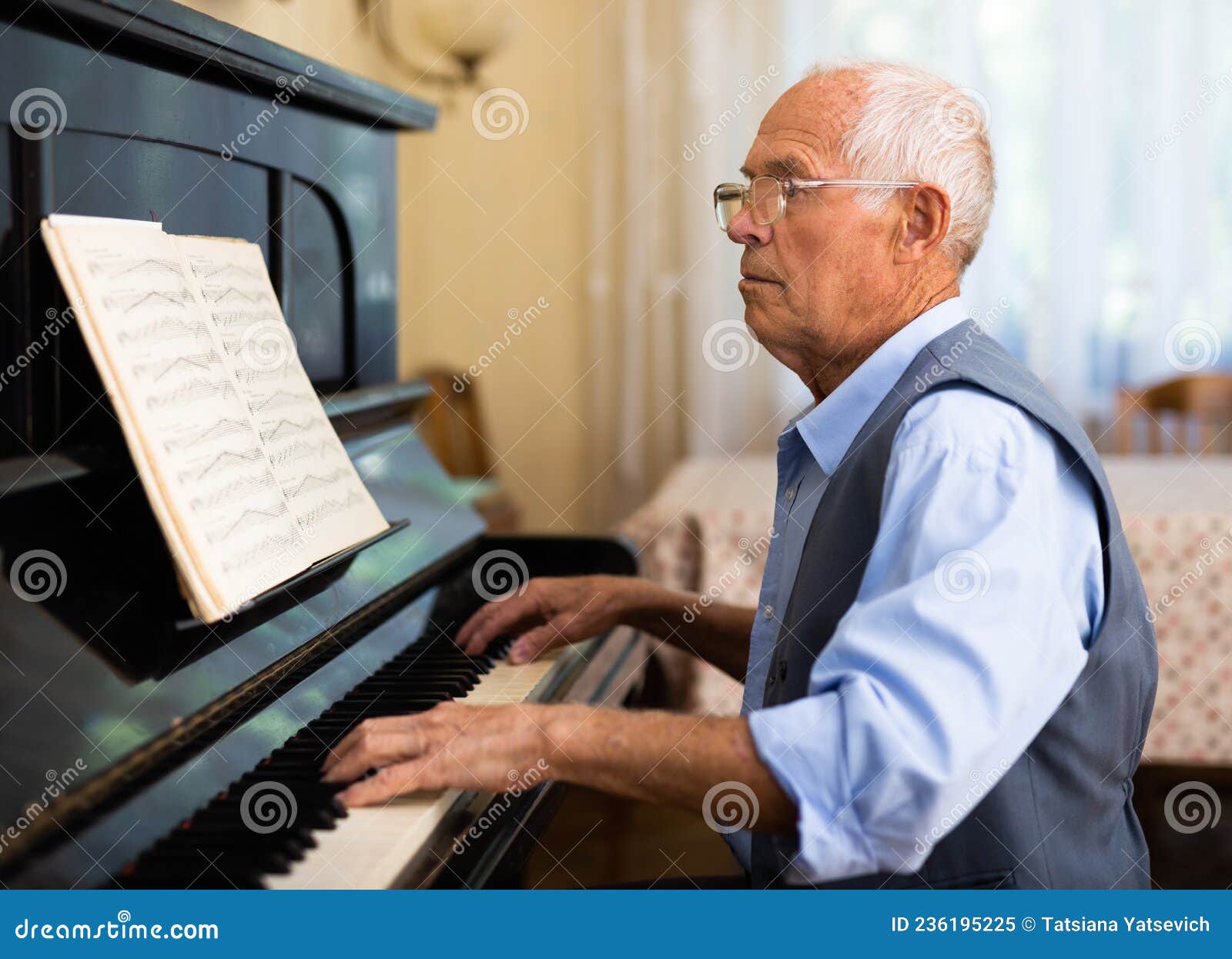 Um homem aprendendo a tocar piano online com um computador em casa