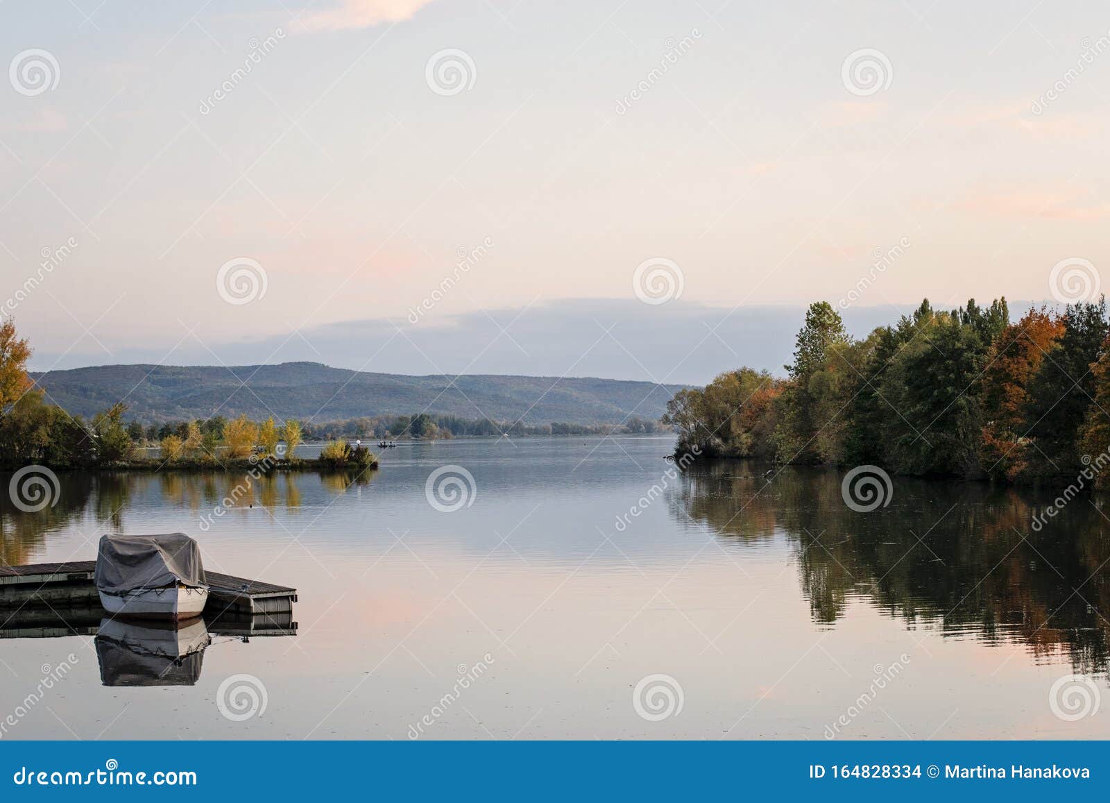 idyllic sunset over lake in autumn. sunset boat on lake. colorful trees reflection in the water. lake slnava, piestany, slovakia.