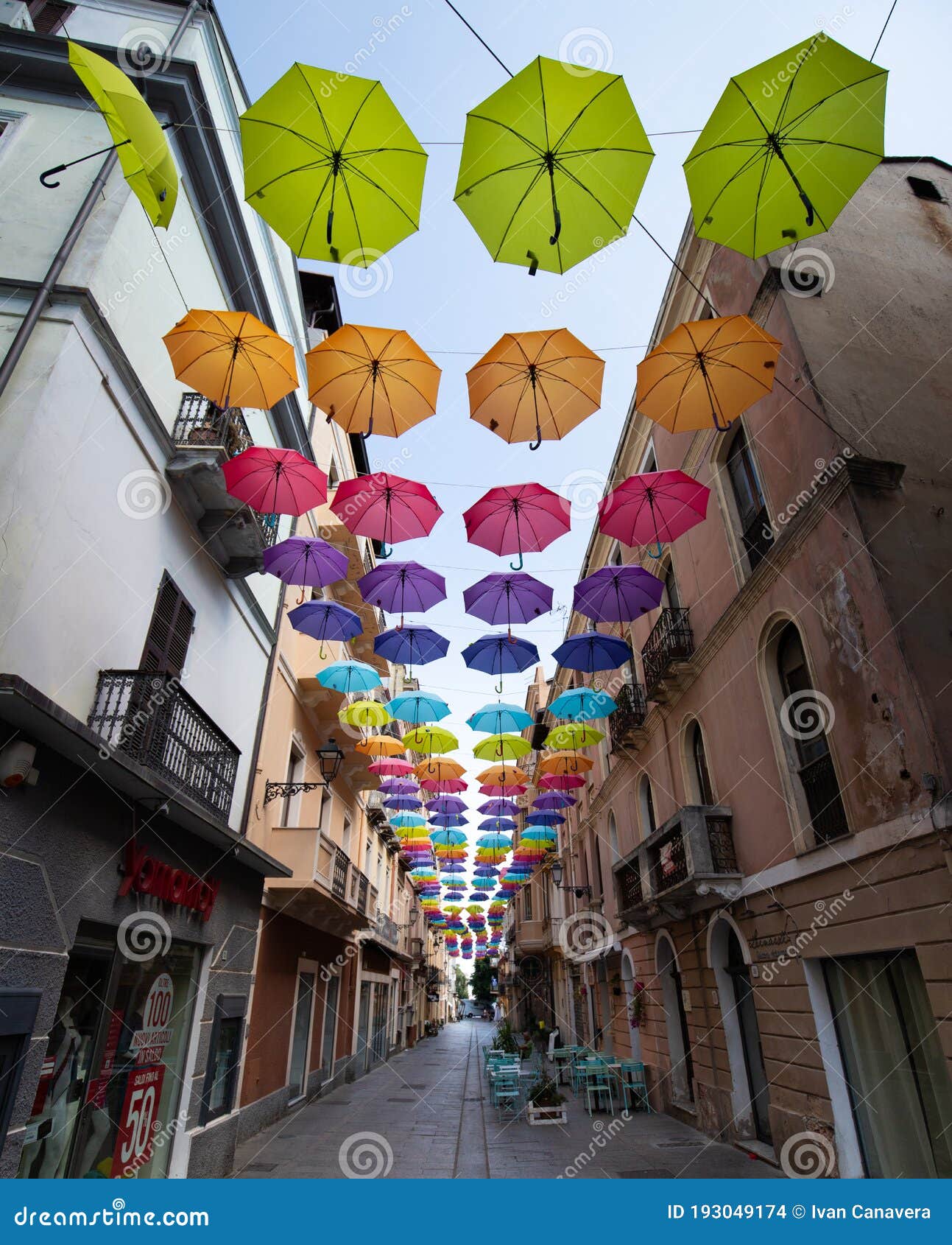 iglesias, italy: colorful umbrellas hanging over a street in old iglesias city in a sunny day