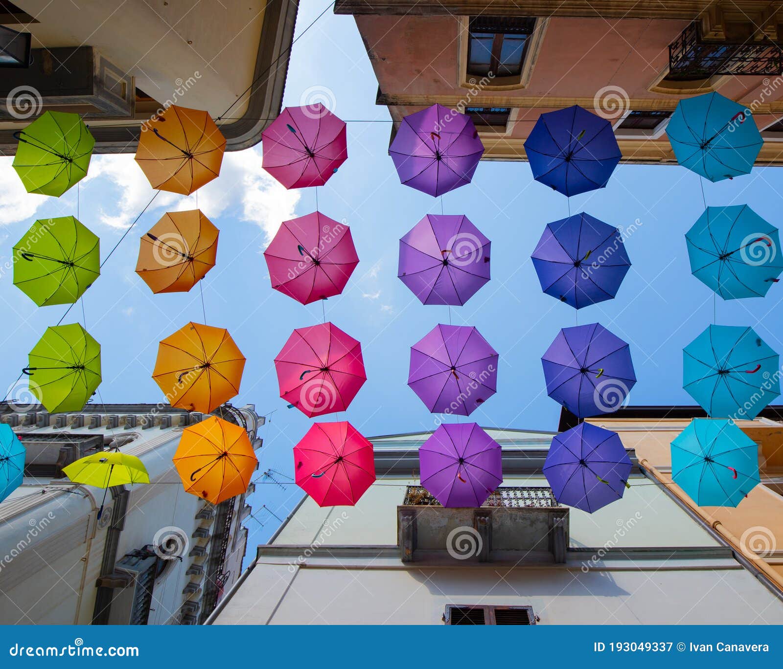 iglesias, italy: colorful umbrellas hanging over a street in old iglesias city in a sunny day