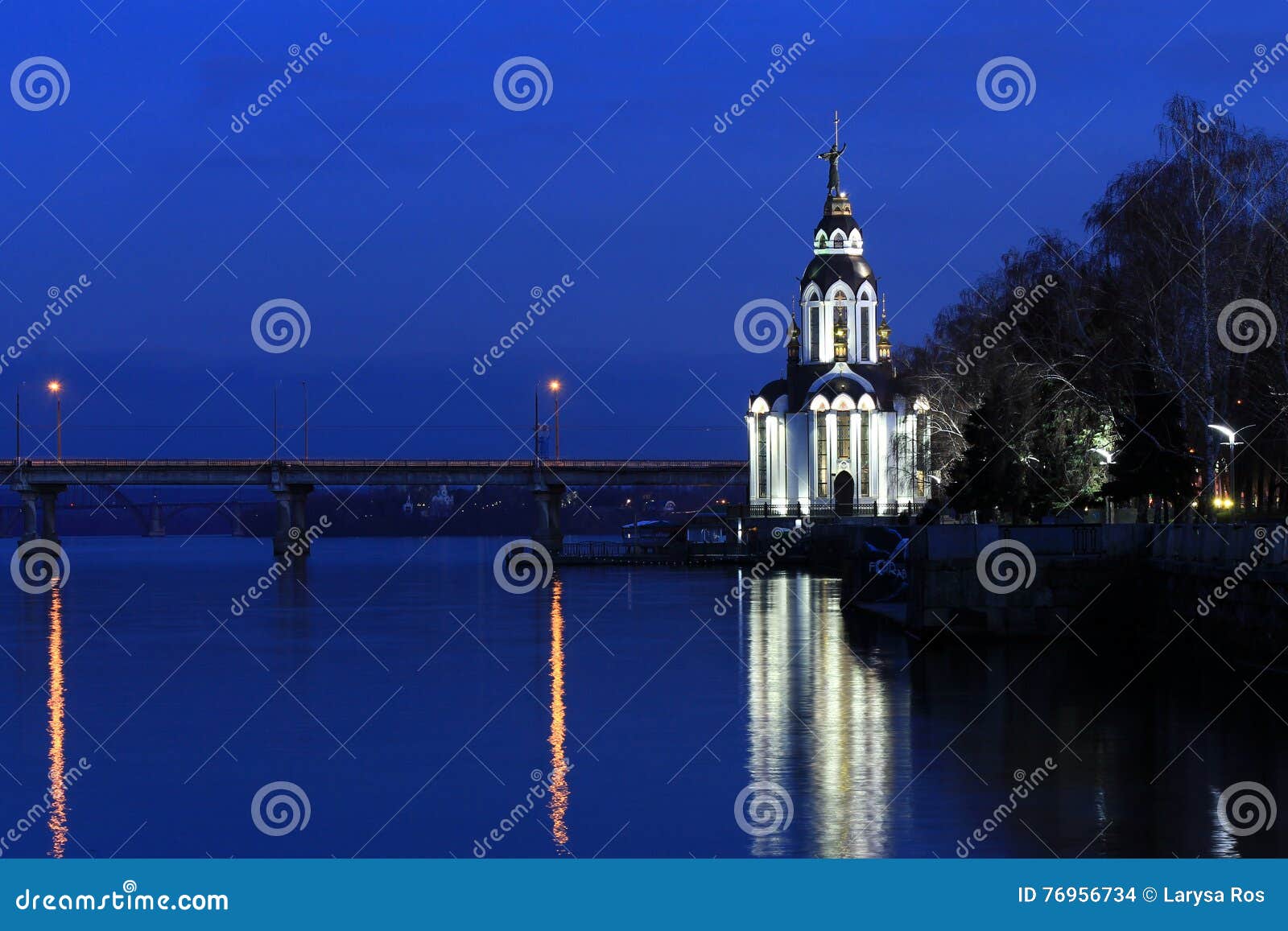 Igreja bonita com iluminação na noite do outono Vista da cidade Dnepr, Dnepropetrovsk, U. A igreja bonita com iluminação na noite do outono, luzes refletiu na água Vista da cidade Dnepr, Dnepropetrovsk, Ucrânia